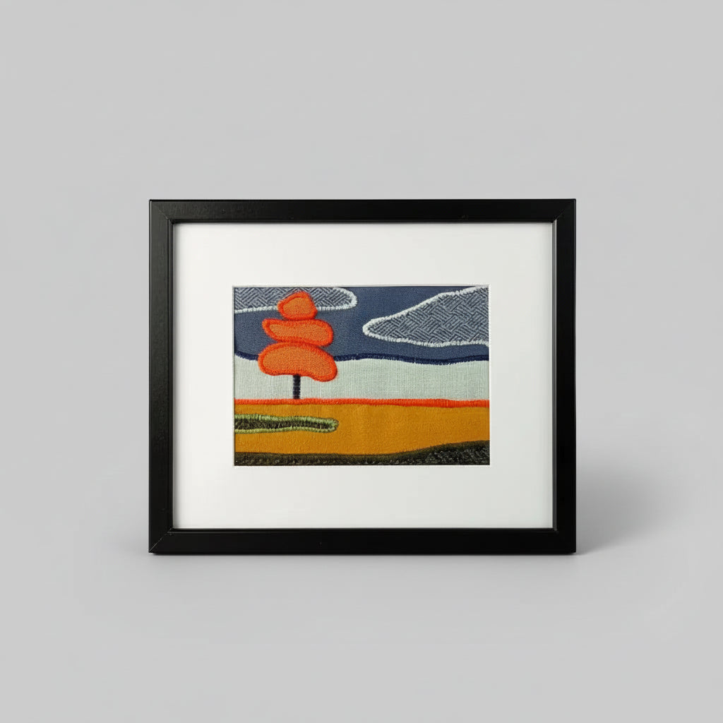 Framed fabric art with single tree in a field landscape
