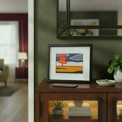 Framed fabric artwork sitting on a hallway cabinet in a contemporary home