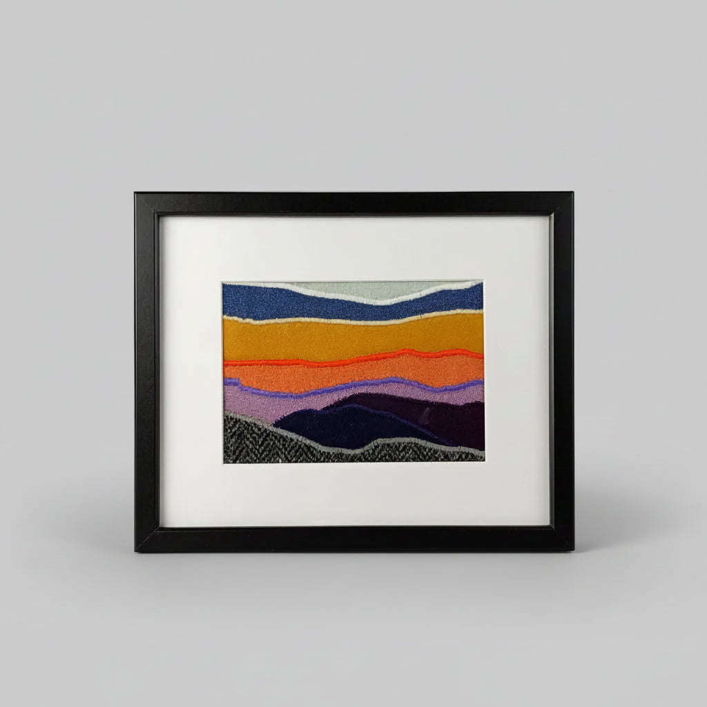 Framed fabric landscape image of a mountaintop and sunset
