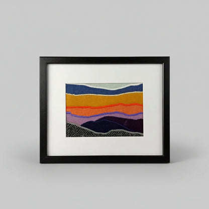 Framed fabric landscape image of a mountaintop and sunset