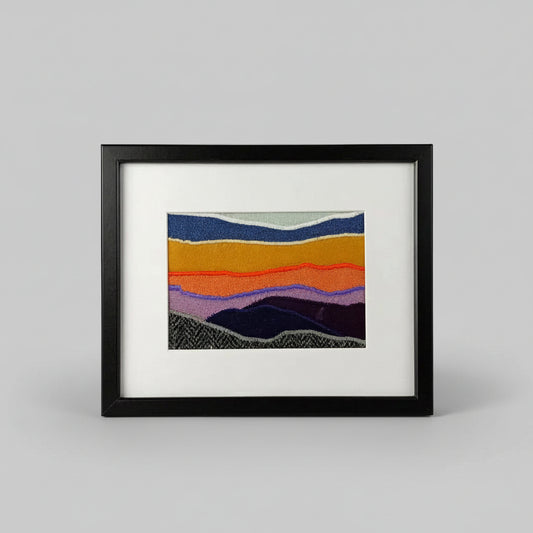 Framed fabric landscape image of a mountaintop and sunset