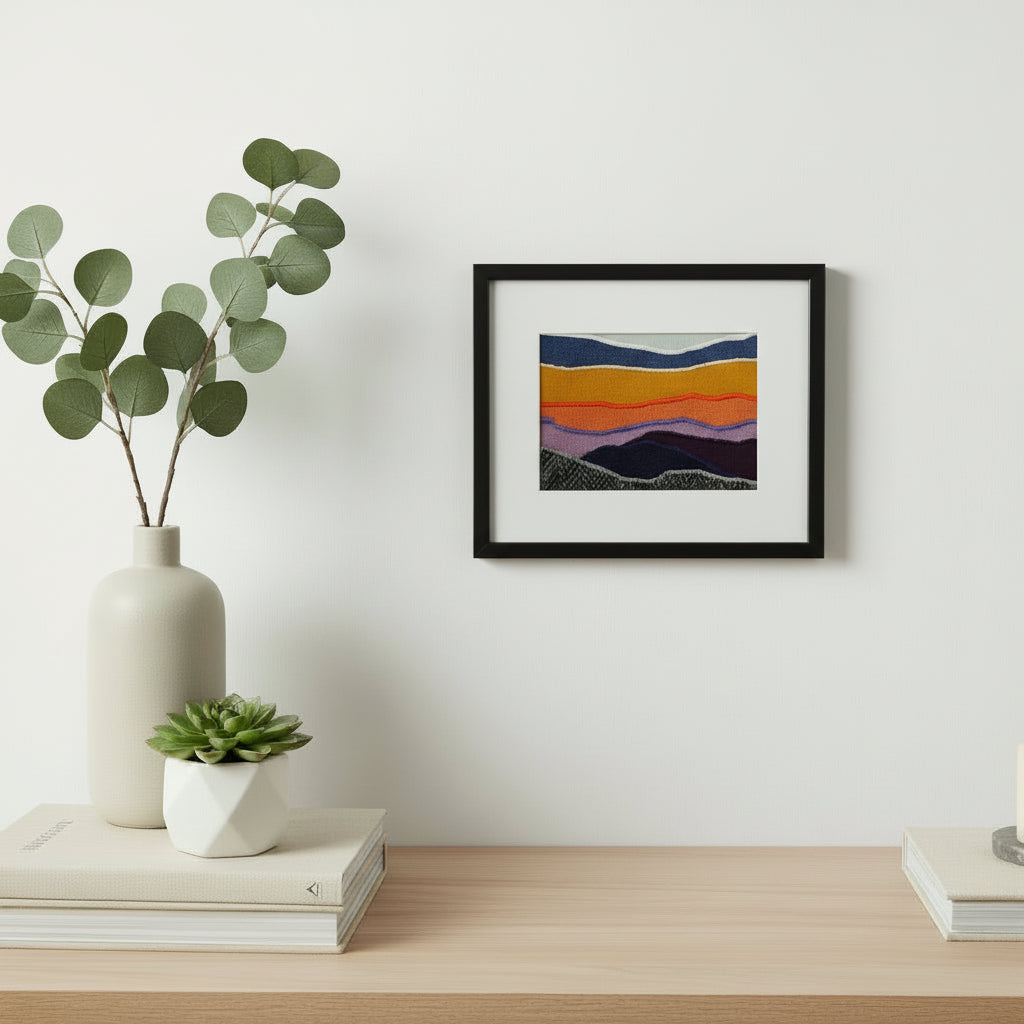 Framed fabric landscape image of a mountaintop and sunset