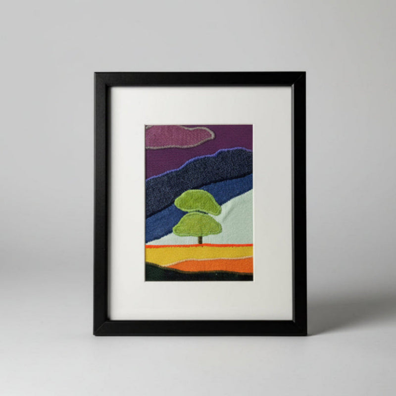 Framed fabric art with a single tree and mountain image