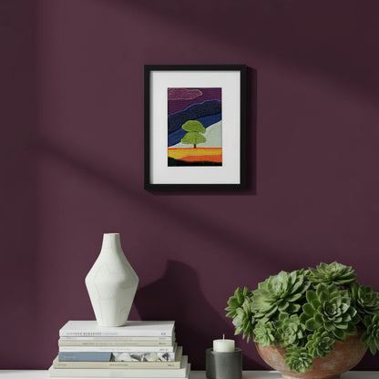 Framed fabric artwork hanging on a purple wall with a modern console table, vase, and plant
