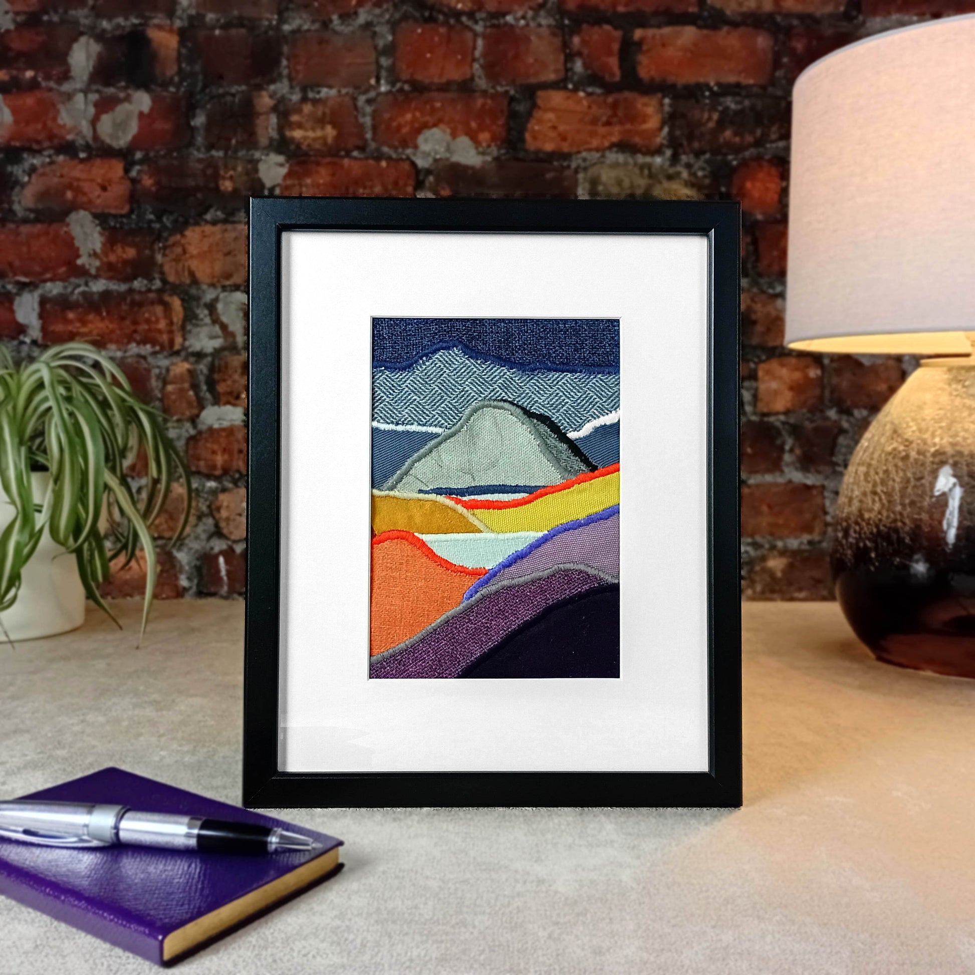 Framed fabric art with mountains and lakes scene