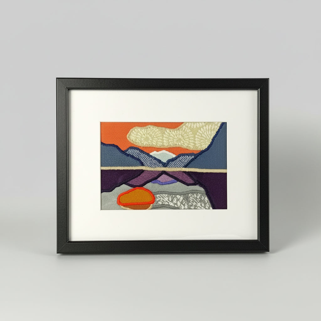 Framed fabric art with a mountain and lake scene