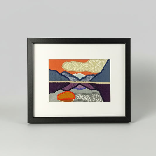 Framed fabric art with a mountain and lake scene