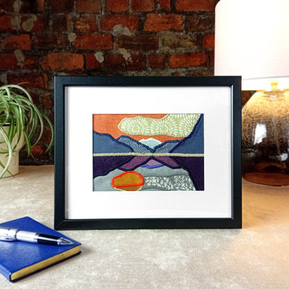 Framed fabric art with a mountain and lake scene