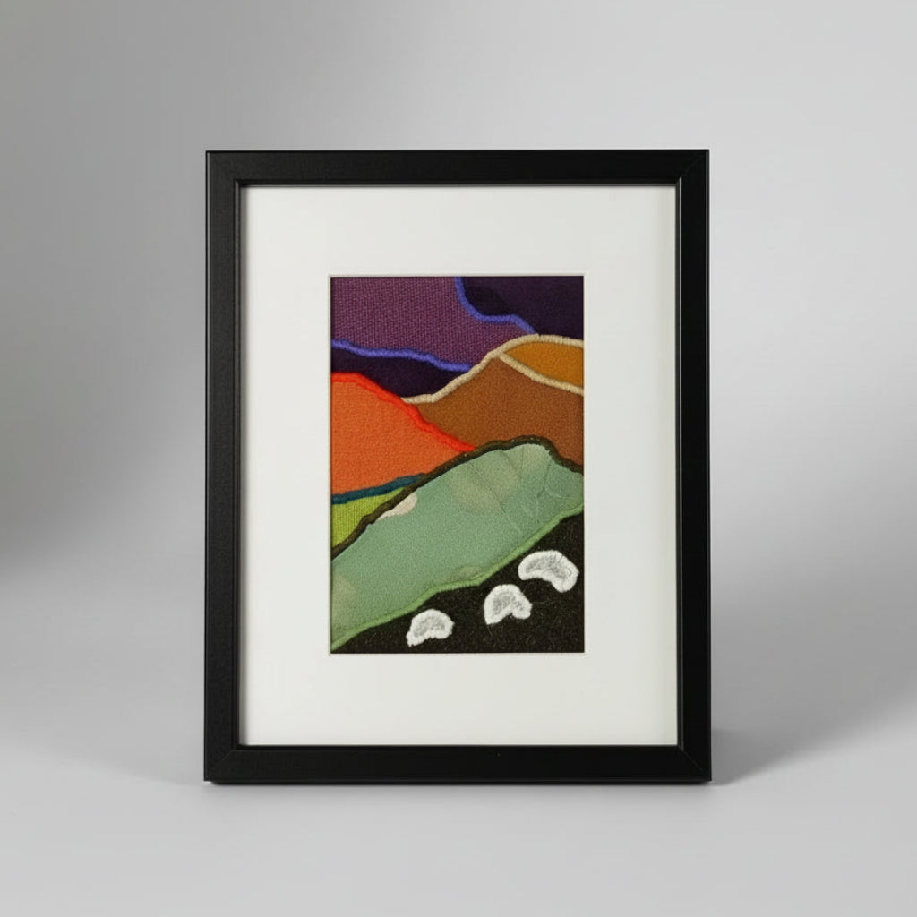 Framed fabric artwork with a hillside landscape featuring highland sheep
