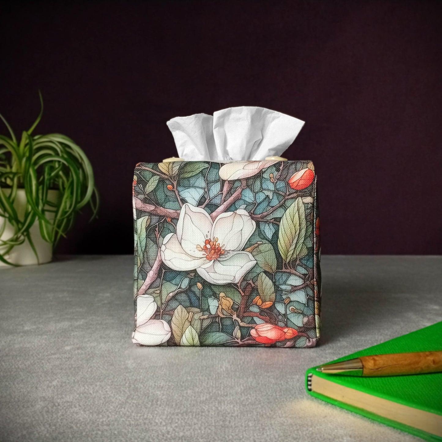 Square tissue box cover with a pen, notebook, and plant