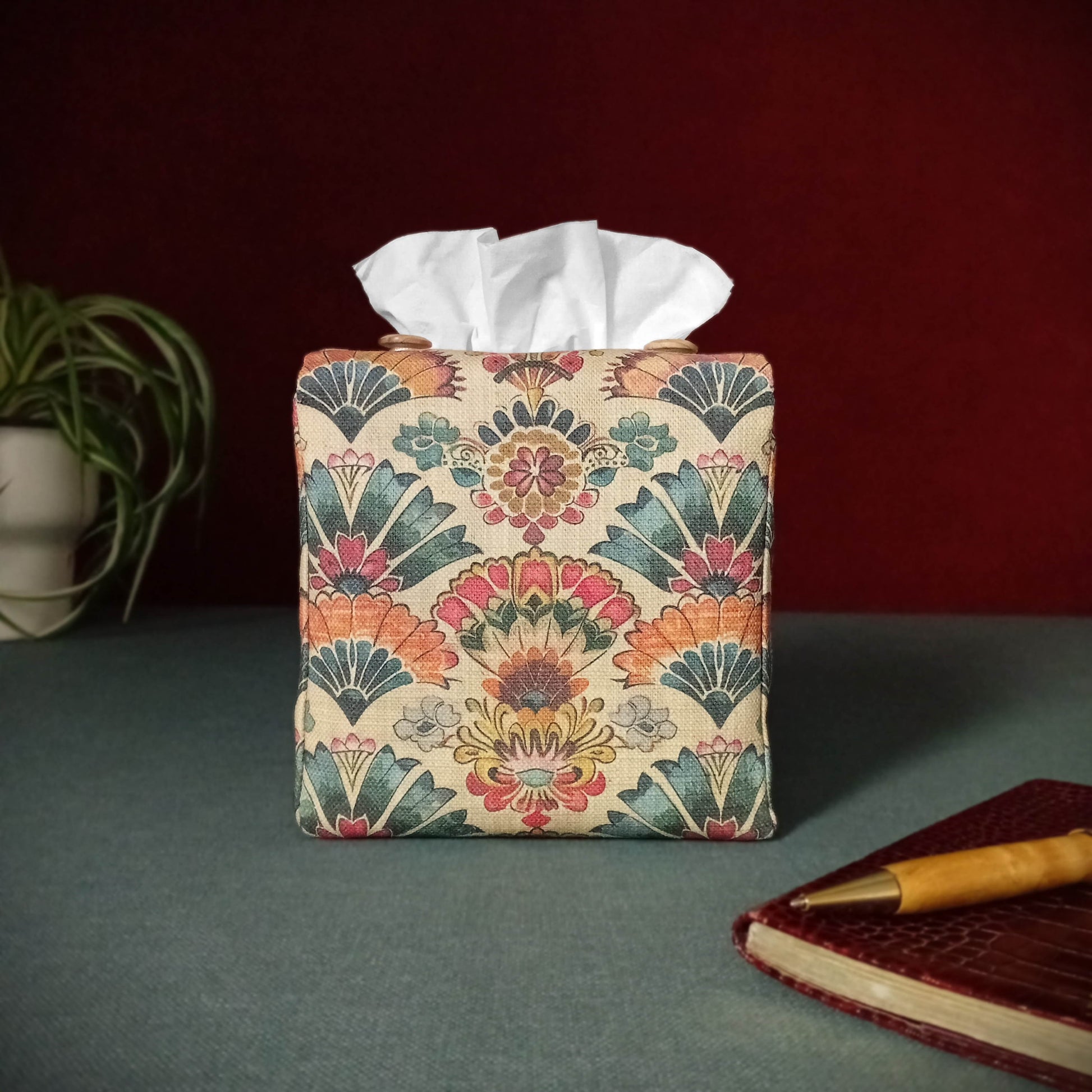 Square tissue box cover with pen, notebook, and plant