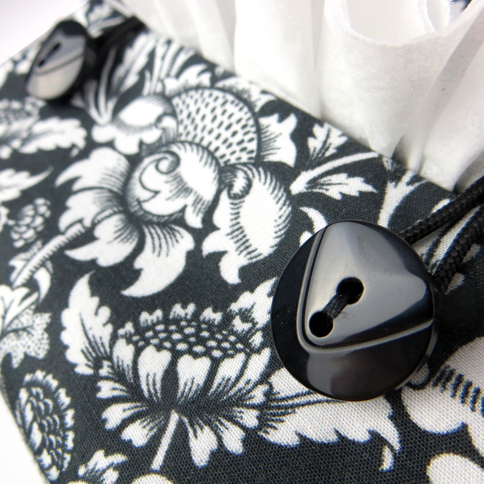 Square tissue box cover with white flowering vine design on black background