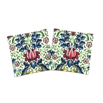 Square coasters with red, blue, green, and yellow flowers and leaves on off white background