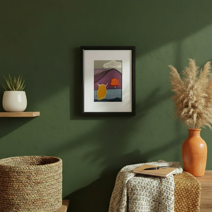 Framed fabric art hanging on a green wall with a shelf, table, and plants