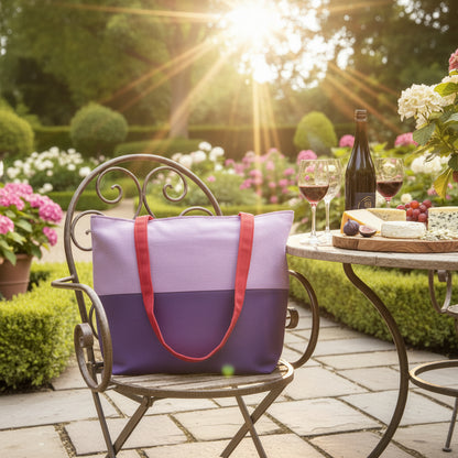 Large cotton tote bag with two vibrant colours on each side sitting on an outdoor patio chair in a formal garden setting