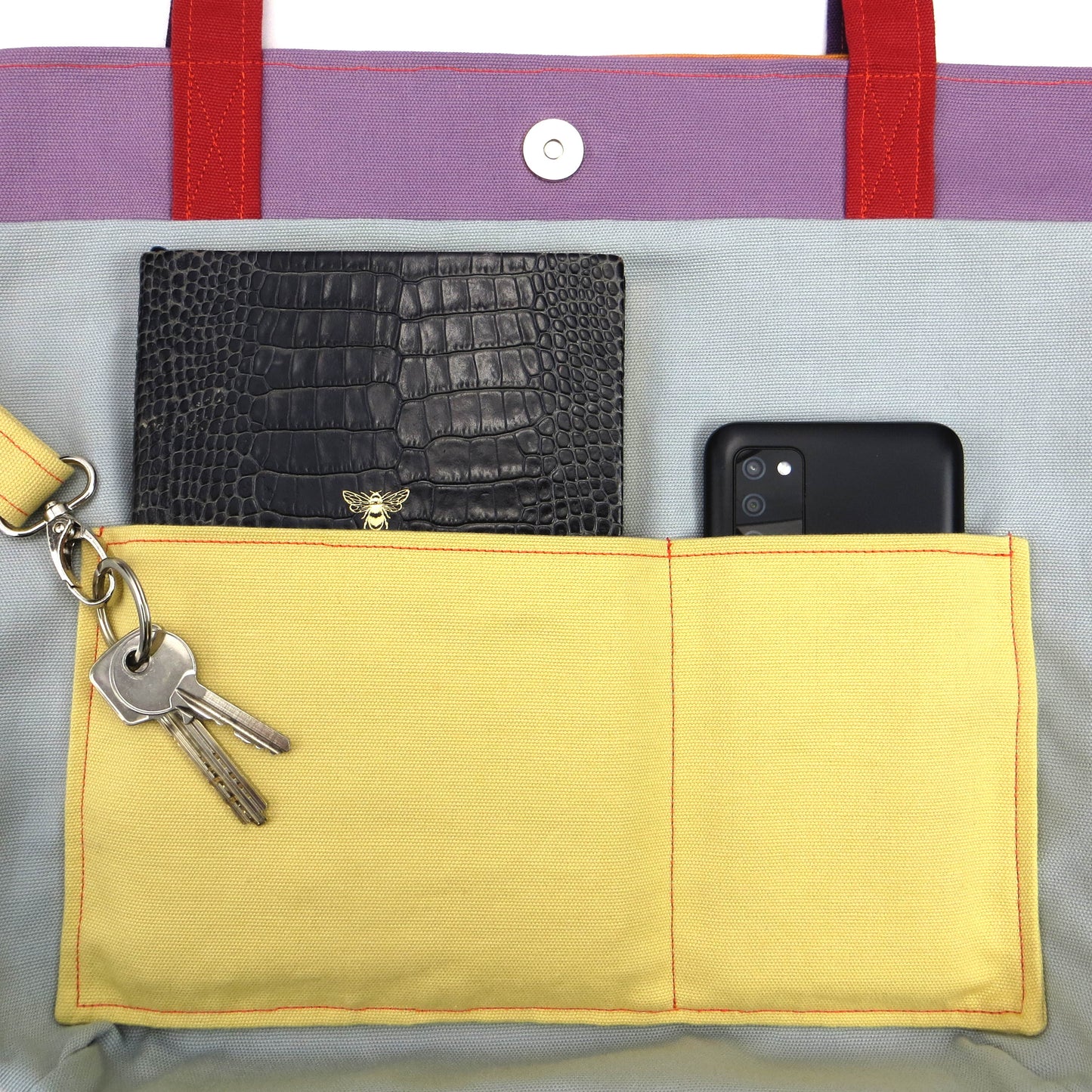 Close up view of a large tote bag interior slip pocket and key clasp