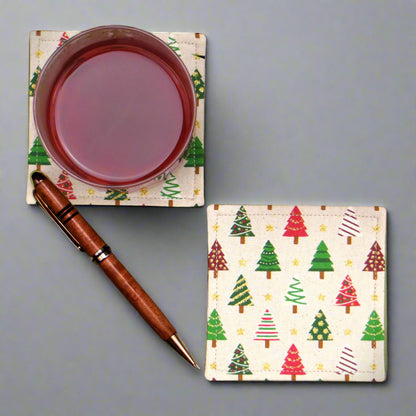Set of two handmade cotton square coasters with a festive holiday design of decorated trees in red, green, and white on a beige background