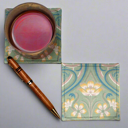 Set of two handmade square coasters with  a Victorian design of yellow flowers with blue embellishments on a sage green background