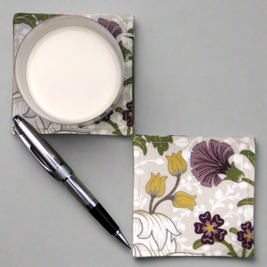 Set of 2 handmade coasters with a white magnolia flower design with accents of green, yellow, and purple