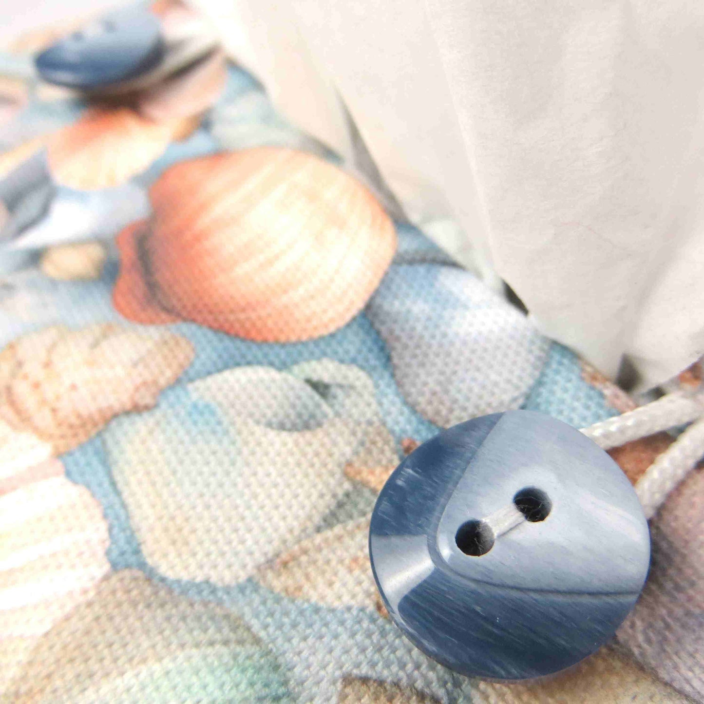 Cotton square tissue box cover with soft pastel seashell images set against a light blue background