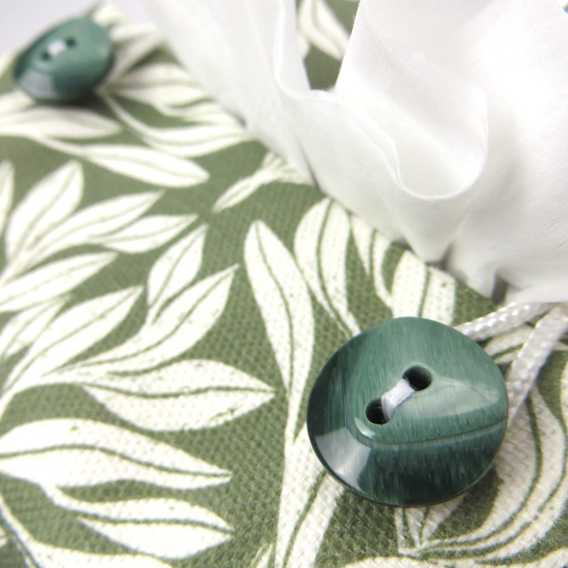 Linen square tissue box cover with an off-white leaf pattern on a sage green background
