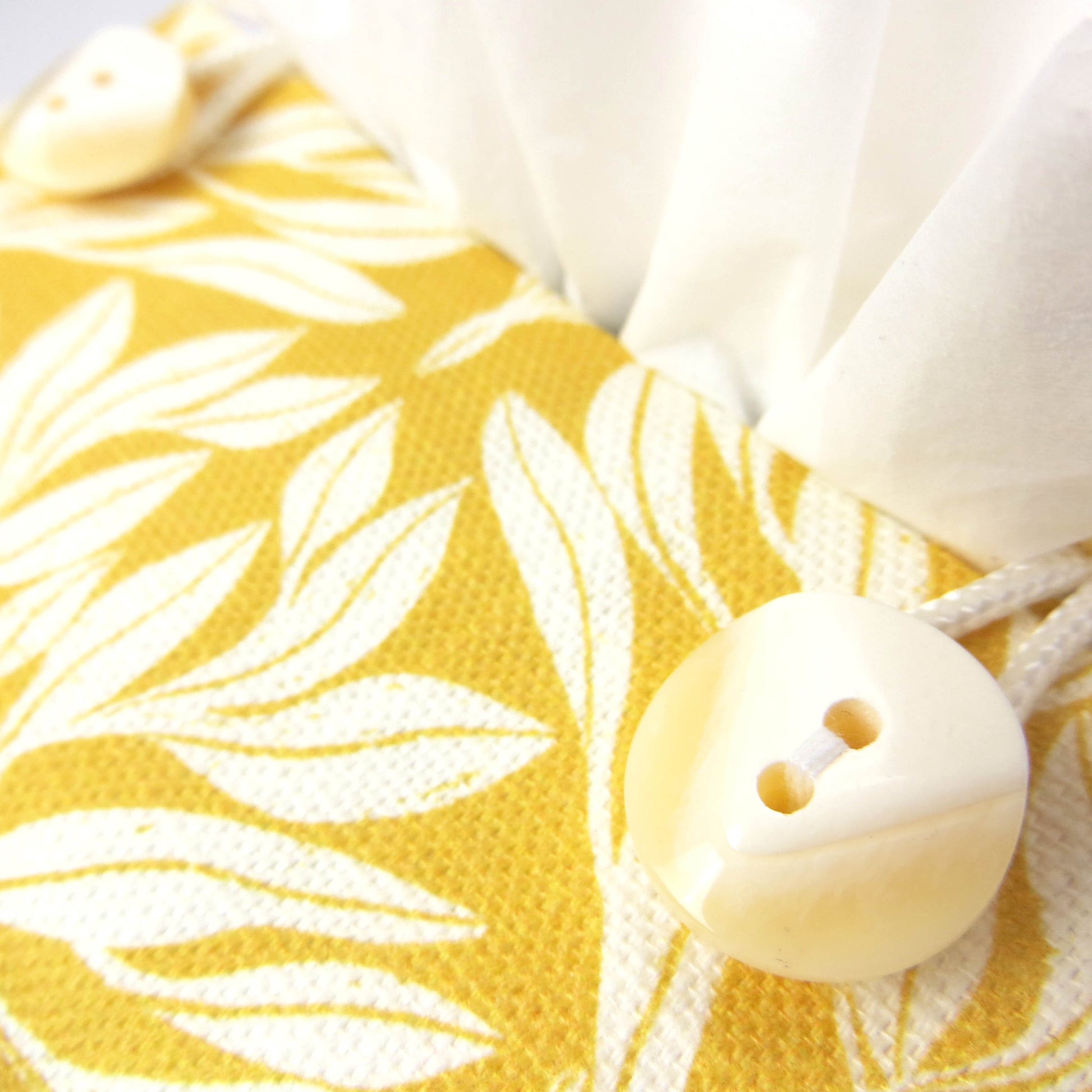 Linen square tissue box cover with an off-white leaf design on a yellow background