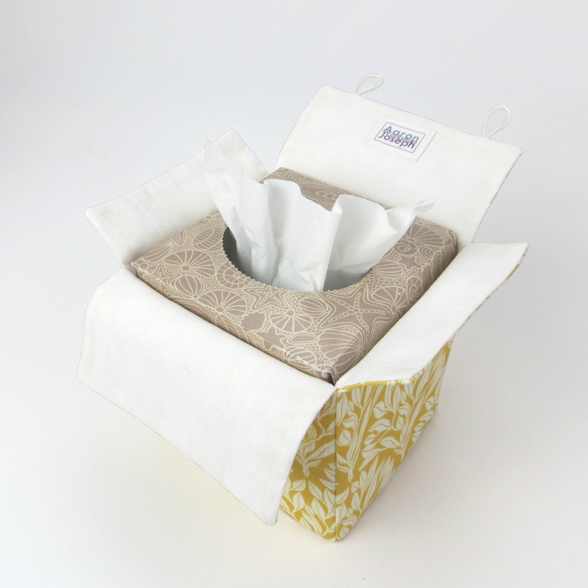 Linen square tissue box cover with an off-white leaf design on a yellow background