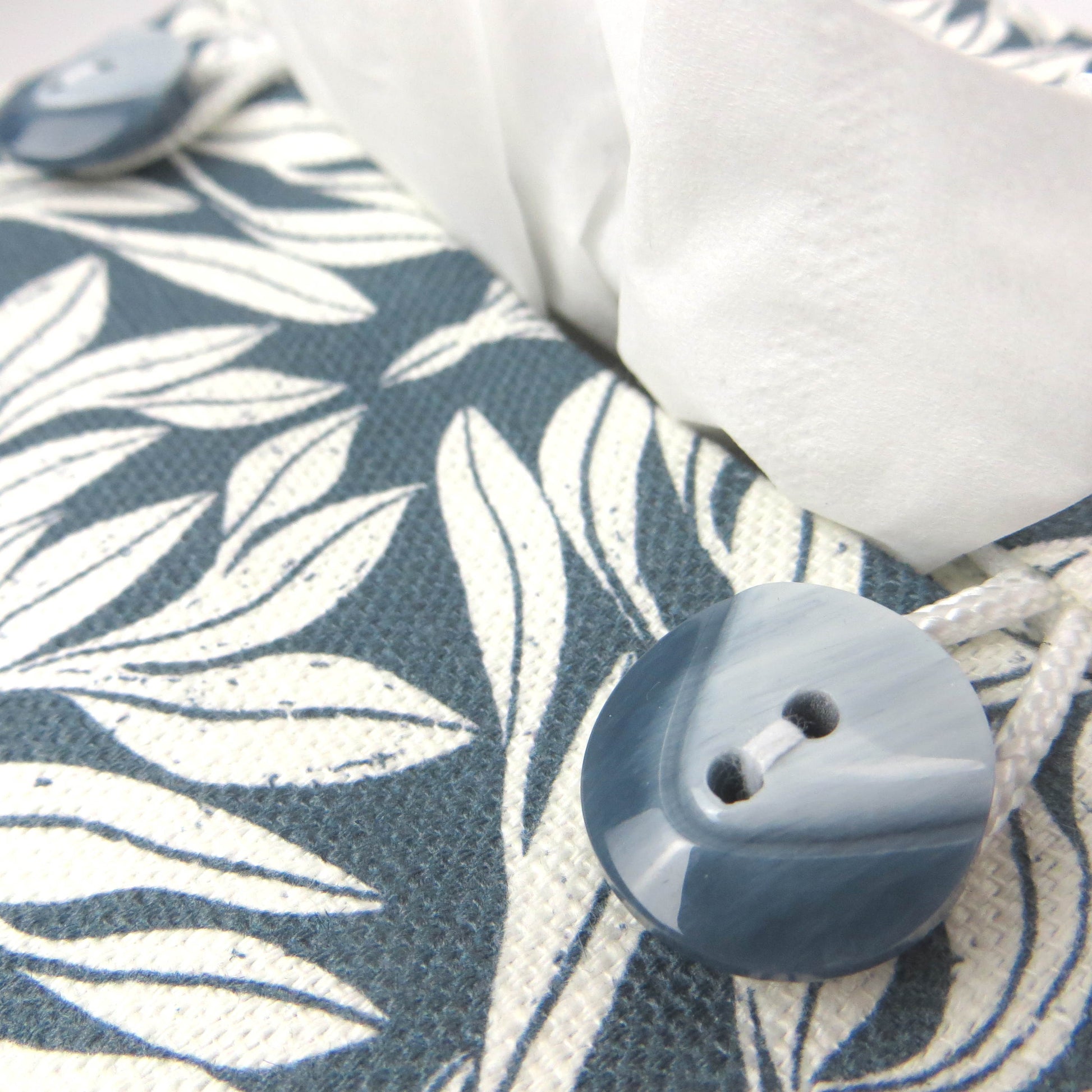 Linen square tissue box cover with an off-white leaf pattern on a blue background