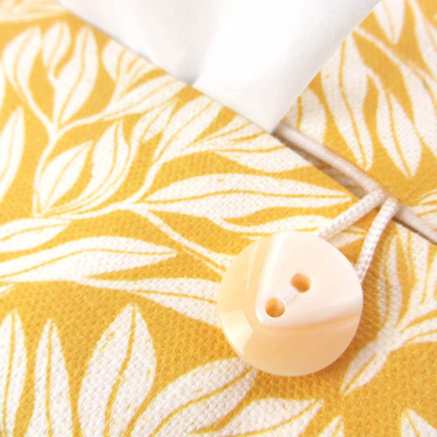 Linen rectangular tissue box cover with an off-white leaf design on a yellow background