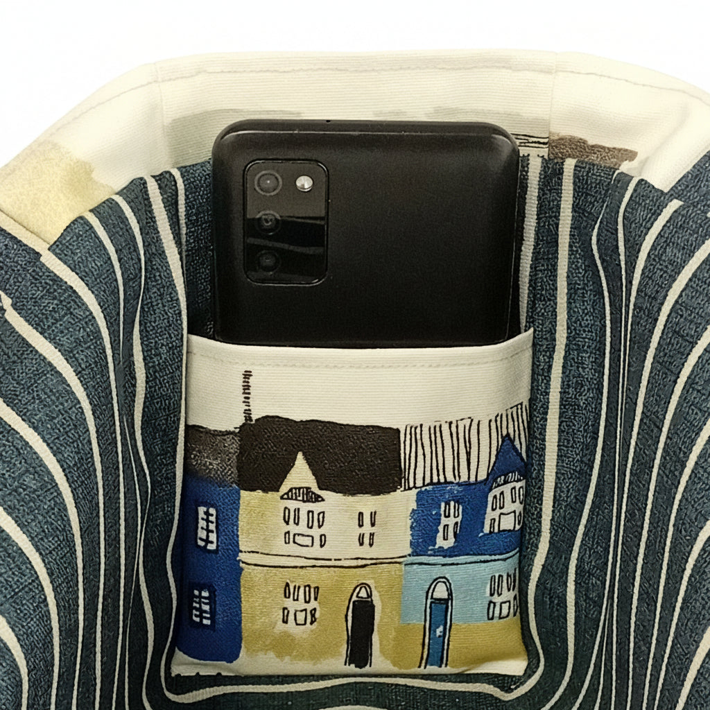 Close up view of the interior slip pocket of a cotton mini tote bag with a seaside and beach themed pattern.