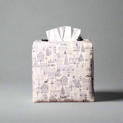 Square tissue box cover with holiday themed winter village scene on off-white background