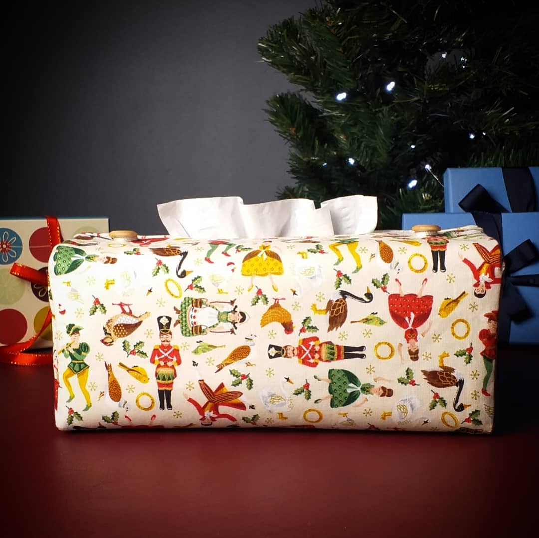 Rectangle tissue box cover with holiday themed 12 days of Christmas icons on cream colour background with Christmas themed decorations