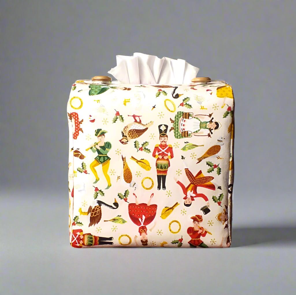 Square tissue box cover with holiday themed icons of the Twelve Days of Christmas on cream background