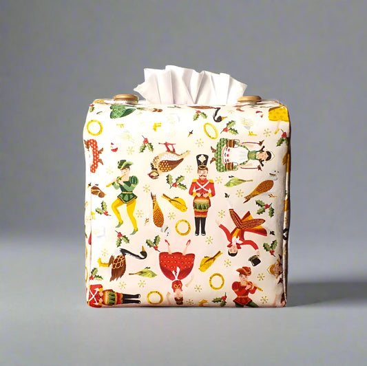 Square tissue box cover with holiday themed icons of the Twelve Days of Christmas on cream background