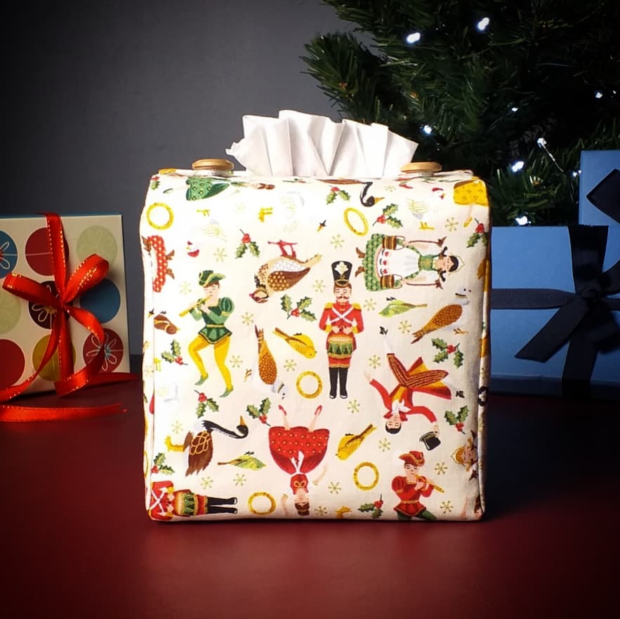 Square tissue box cover with holiday themed icons of the Twelve Days of Christmas on cream background with Christmas themed decor