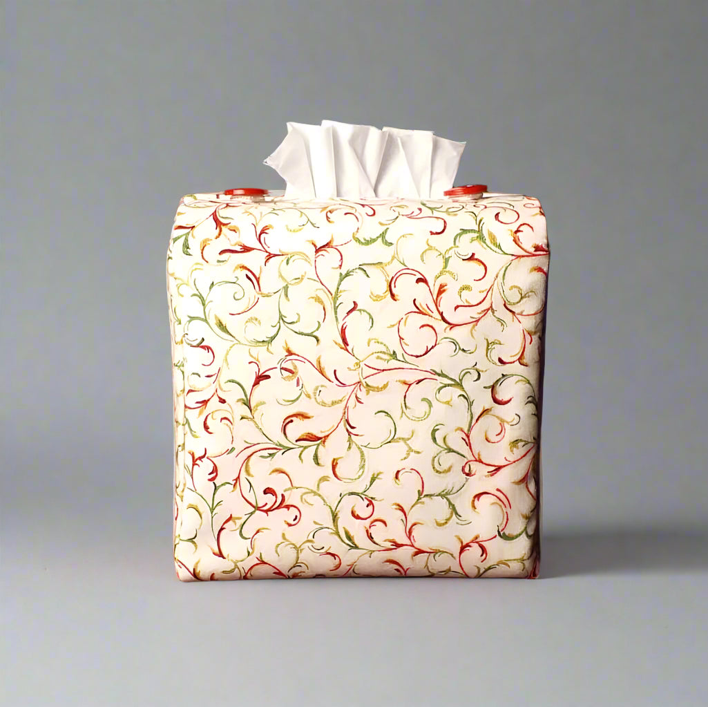 Square tissue box cover with holiday themed red and green swirls with metallic gold accent on cream colour background