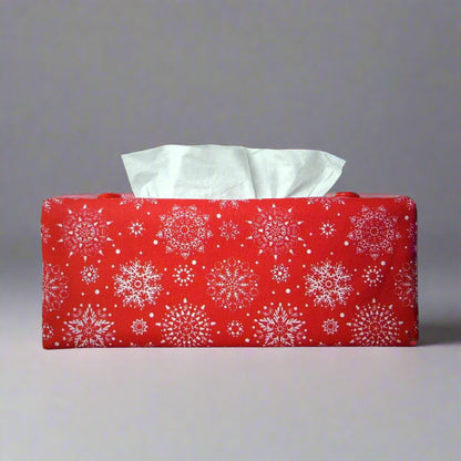 Rectangular tissue box cover with holiday themed white snowflake design on red background