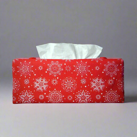 Rectangular tissue box cover with holiday themed white snowflake design on red background