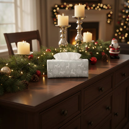 Rectangular tissue box with holiday themed white reindeer cover sitting on a sideboard in a Christmas decorated living room