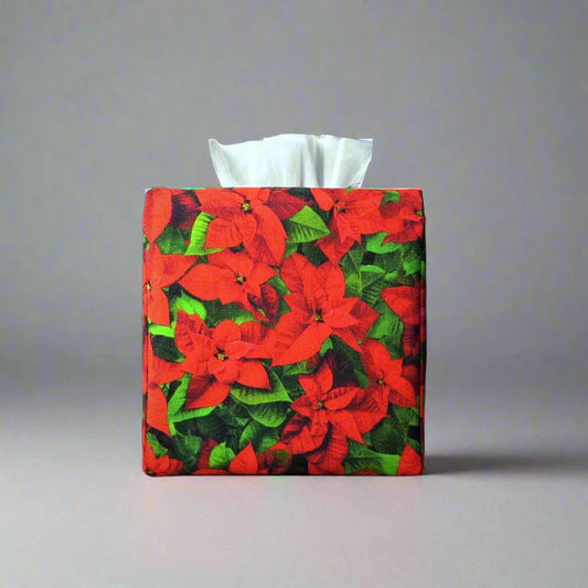 Square tissue box cover with holiday themed poinsettia design on green leaf pattern background