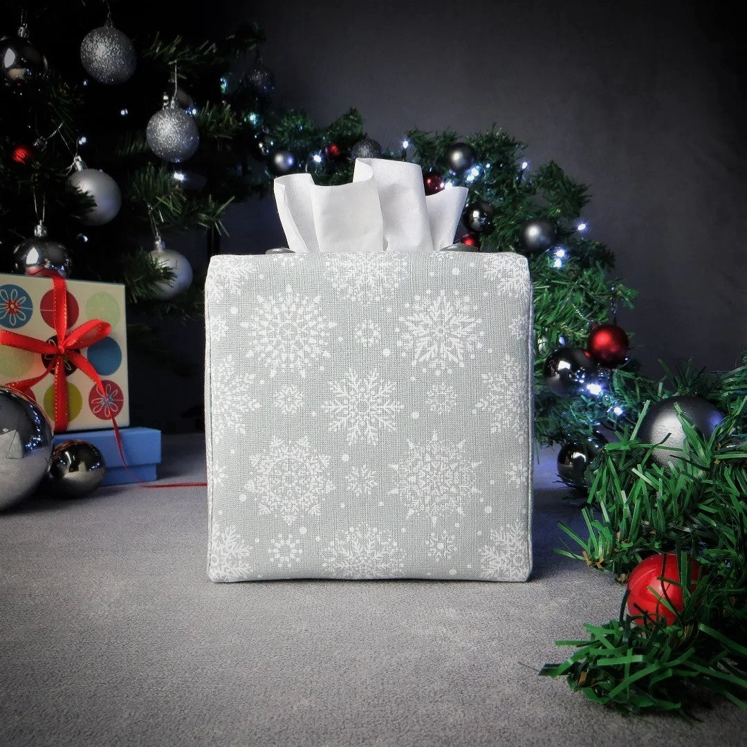 Square tissue box cover with winter themed white snowflakes design on grey background with Christmas themed decor