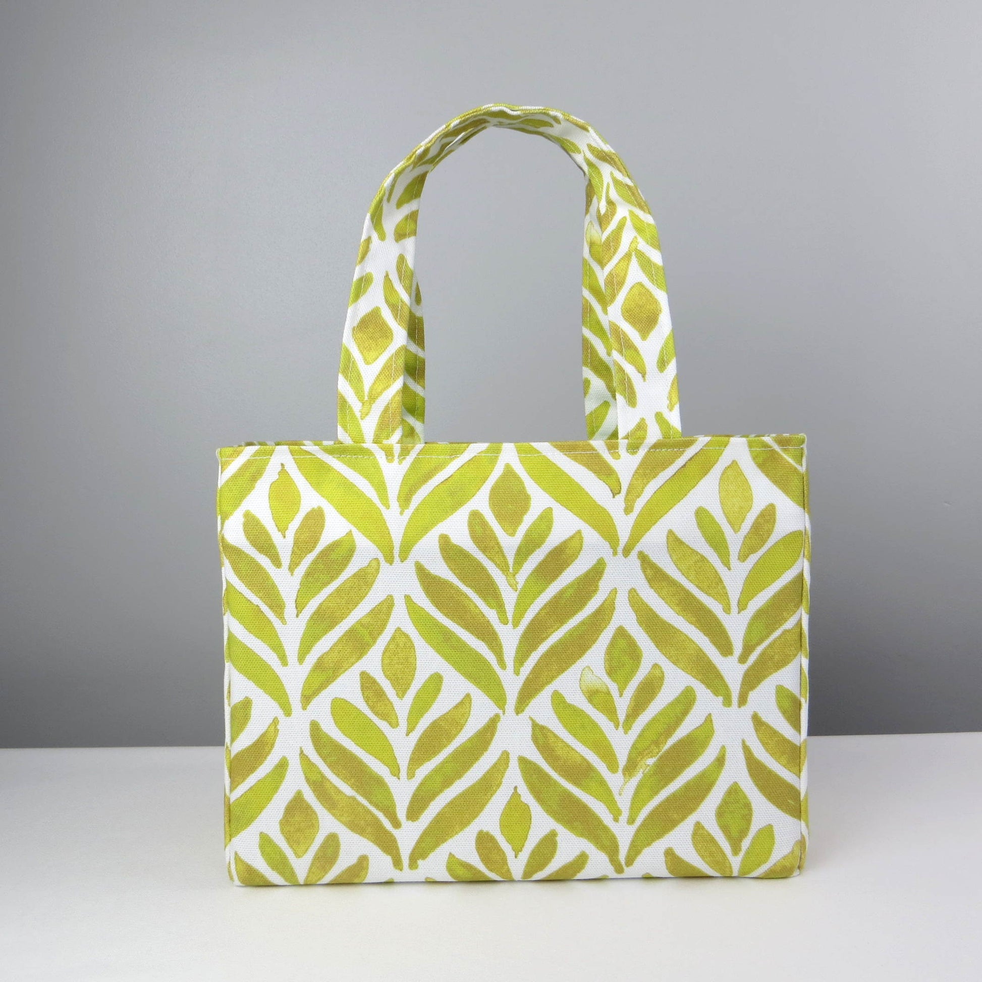 Front view of a mini tote bag with yellow watercolour style leaf pattern on background