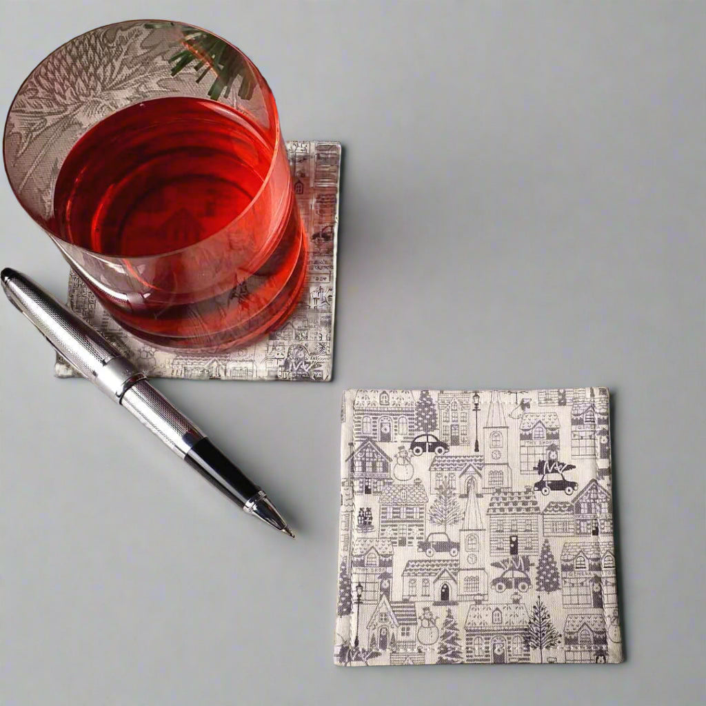 Square coasters with holiday themed winter village scene on off-white background