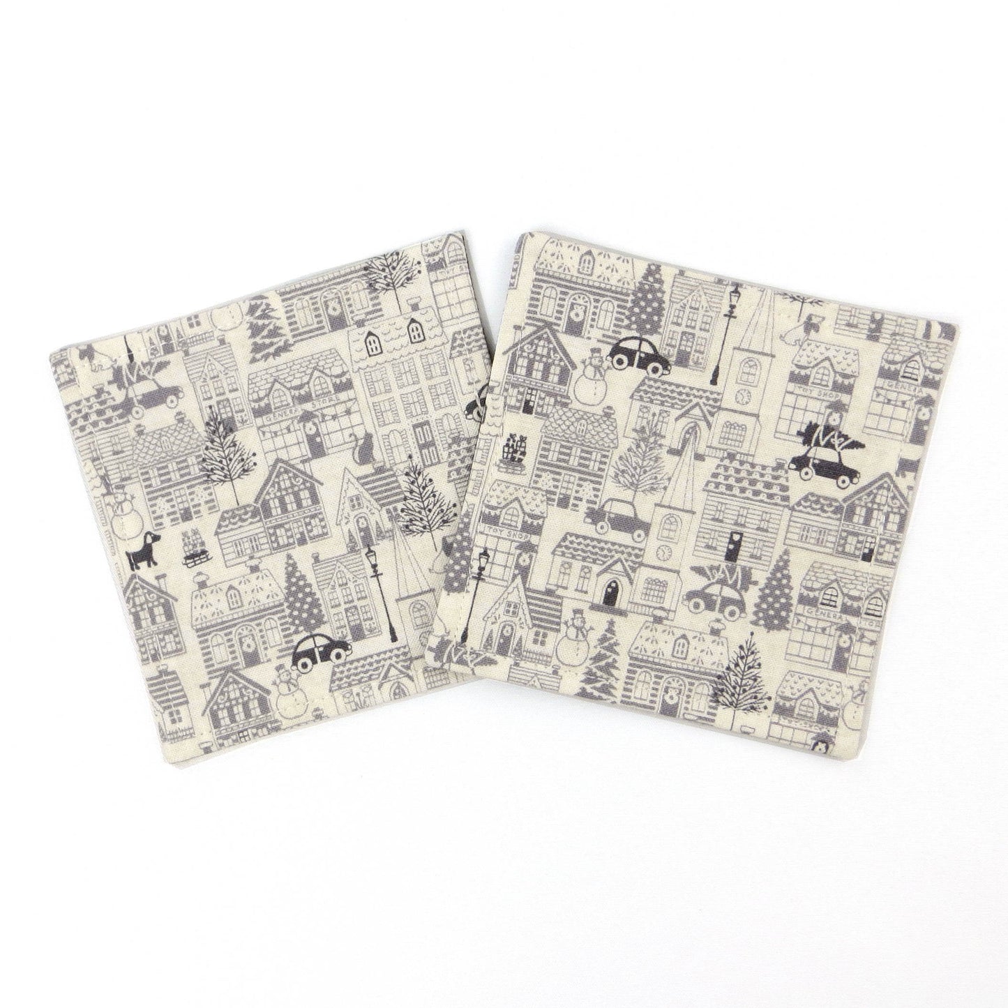 Square coasters with holiday themed winter village scene on off-white background