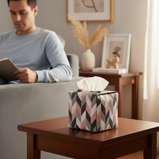 Handmade tissue box cover with pink, white, and grey herringbone design displayed in a living room