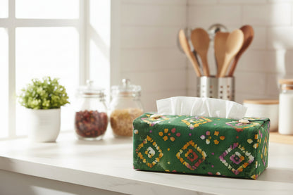Rectangular tissue box cover with orange diamond design on a green background displayed in a kitchen