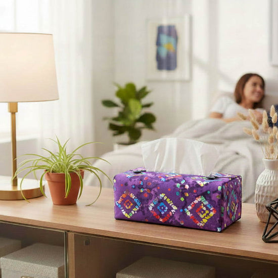 Rectangular tissue box cover with multi colour diamonds design on purple background displayed in a bedroom