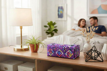 Rectangular tissue box cover with multi colour diamonds design on purple background displayed in a bedroom