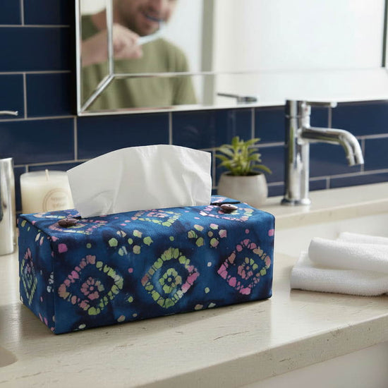 Rectangular tissue box cover with magenta and green diamonds on a blue background displayed in a bathroom