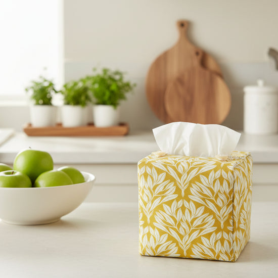 Handmade linen cube tissue box cover with floral design on yellow background displayed in a kitchen